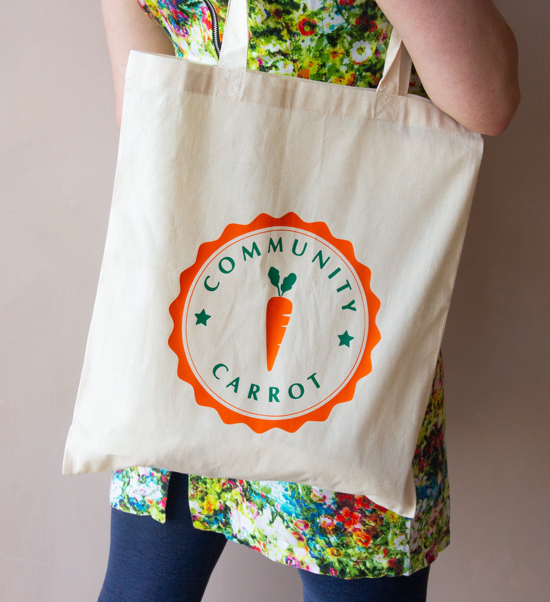 Woman in bright floral dress carrying a Community Carrot Linen Bag