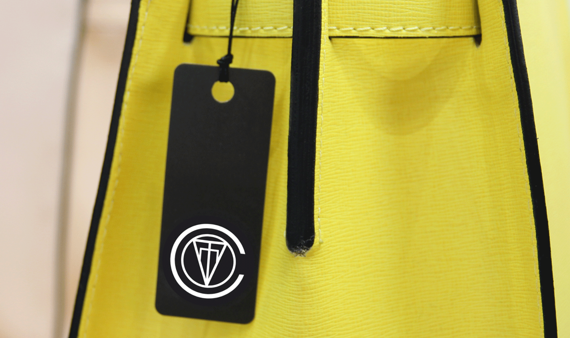 Covet tag hangs from a bright yellow leather bag